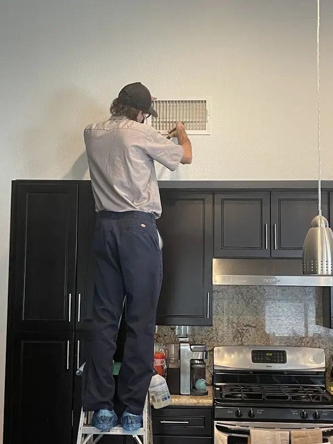 Technician inspecting an air vent during HVAC service in Dakota Ridge